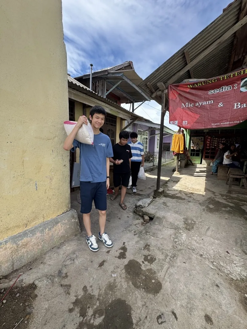 A volunteer carries a sack of rice on his shoulder down a village street