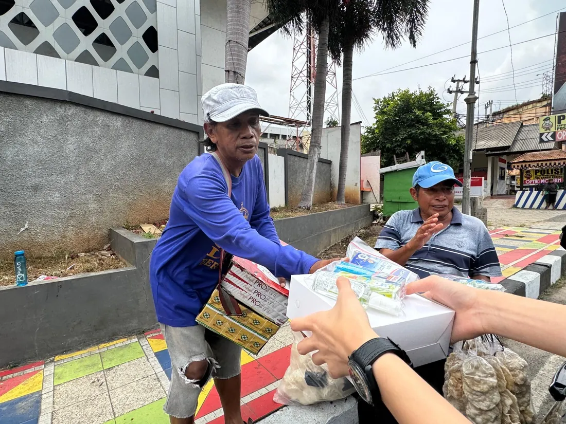 A man in a blue shirt reaches for a care package on a colorful sidewalk