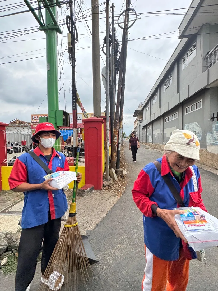 Two street sweepers in uniform hold their care packages, one smiling