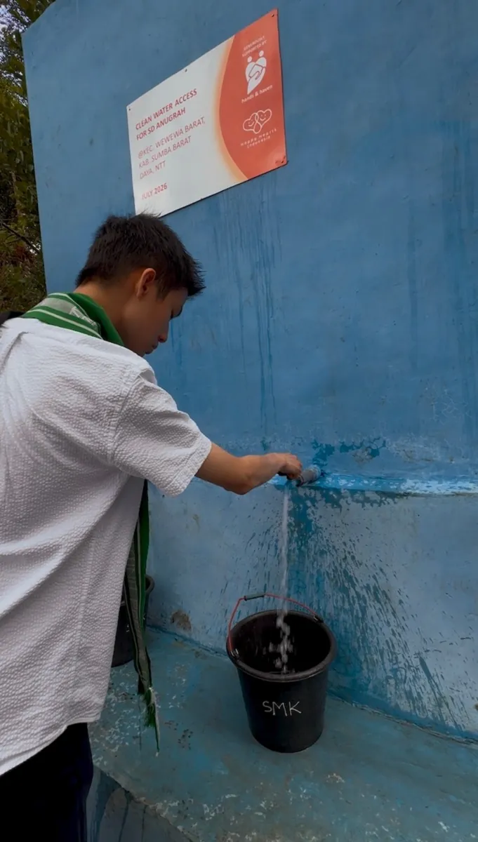 Bryan Wu opens a tap on the new well and water pours into a bucket